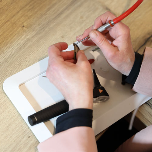 Zwei Hände reinigen ein Hörgerät